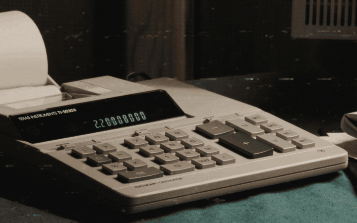 A mallet smashing an old desk calculator