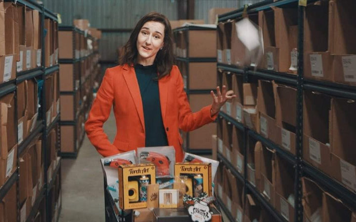 Darby Cox in a warehouse aisle with an order cart full of products